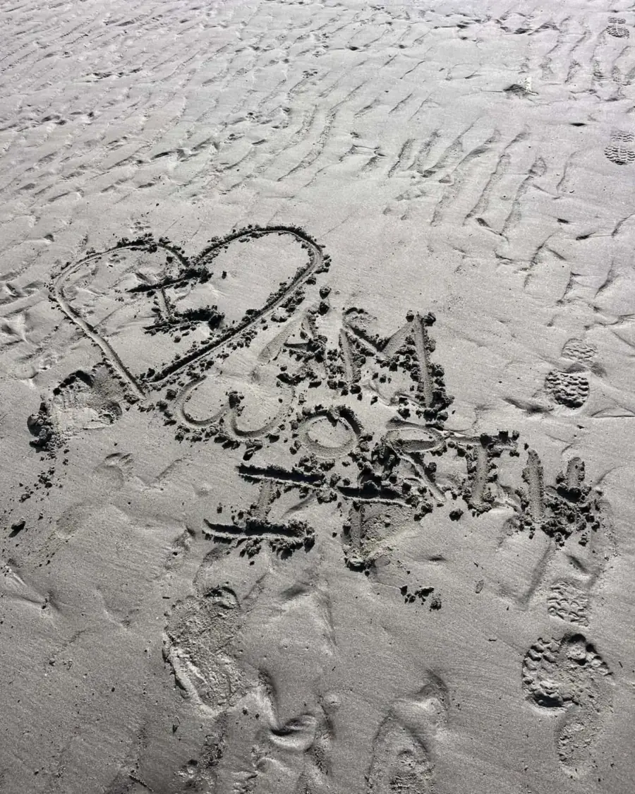 The words "I am worth it" and a heart drawn by hand in the wet sand on a beach